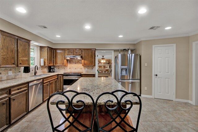 kitchen featuring light stone countertops, sink, a kitchen island, and appliances with stainless steel finishes