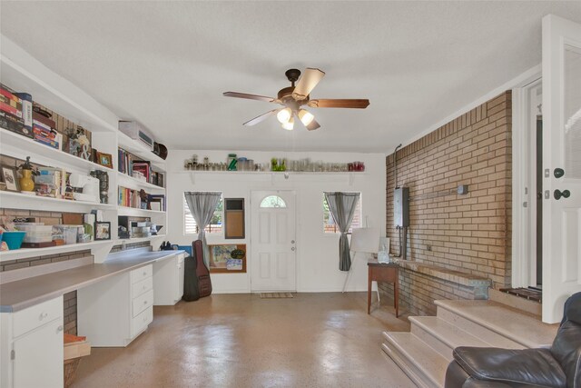 home office featuring ceiling fan, plenty of natural light, brick wall, and a textured ceiling