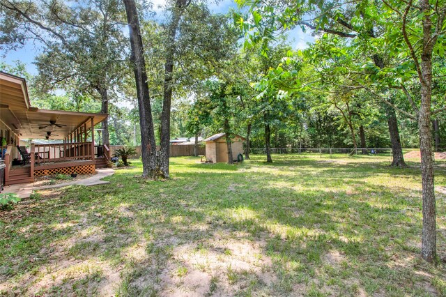 view of yard with a deck, ceiling fan, and a storage shed