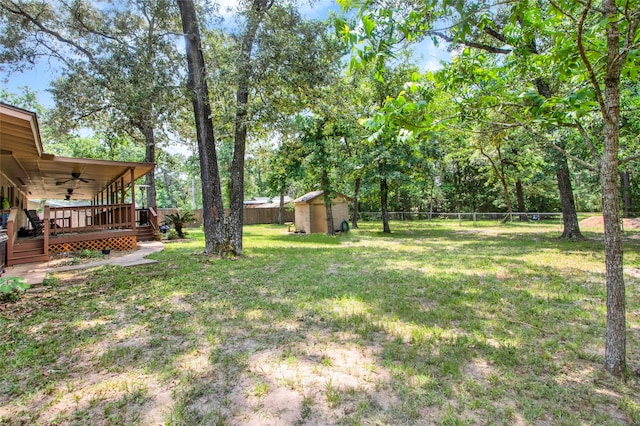 view of yard featuring ceiling fan, a deck, and a shed