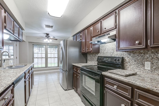 kitchen with sink, light tile patterned floors, a textured ceiling, appliances with stainless steel finishes, and tasteful backsplash