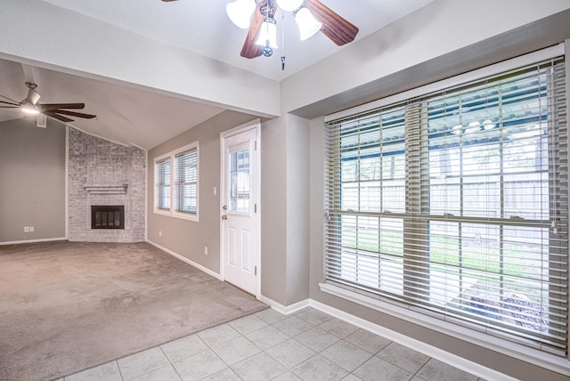 unfurnished living room featuring a fireplace, a healthy amount of sunlight, light carpet, and vaulted ceiling