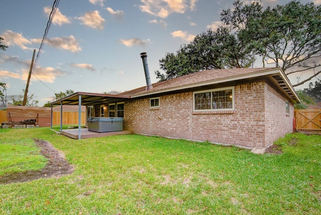 rear view of house with a yard and a hot tub