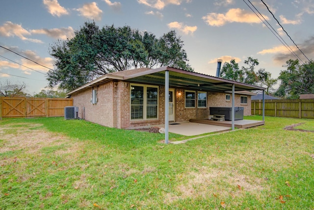 rear view of house featuring a yard, cooling unit, a patio, and a hot tub