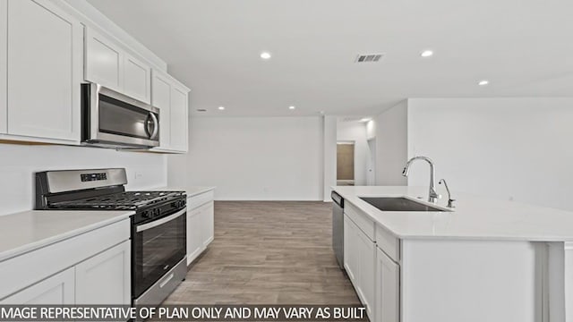 kitchen featuring white cabinetry, sink, light hardwood / wood-style flooring, an island with sink, and appliances with stainless steel finishes