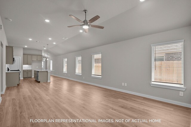 unfurnished living room with a sink, light wood-type flooring, baseboards, and vaulted ceiling