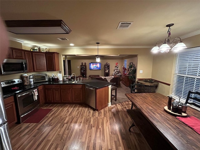 kitchen featuring kitchen peninsula, appliances with stainless steel finishes, decorative light fixtures, and a notable chandelier