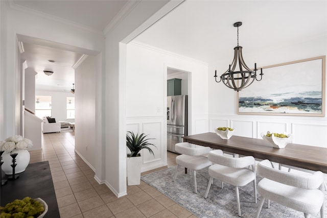 tiled dining space featuring ceiling fan with notable chandelier and ornamental molding