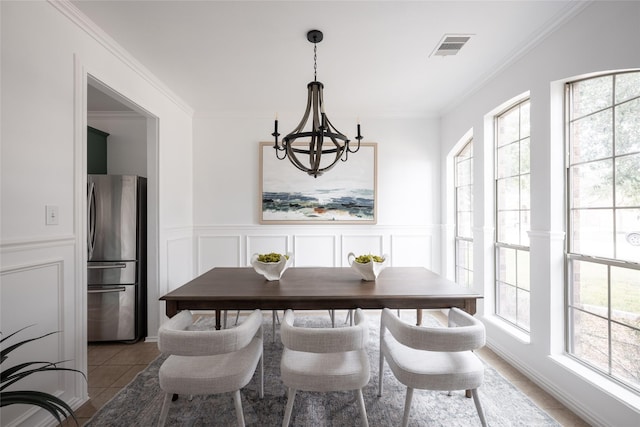 tiled dining space with ornamental molding and a notable chandelier