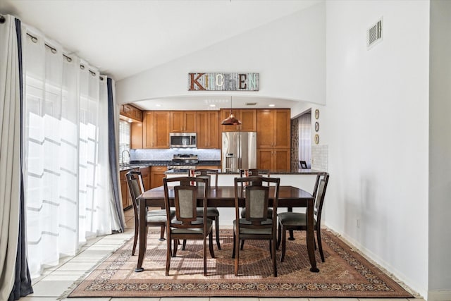 tiled dining room featuring high vaulted ceiling