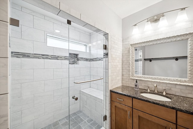 bathroom featuring vanity, a shower with shower door, and backsplash