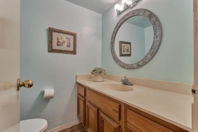 bathroom with vanity, toilet, and a textured ceiling