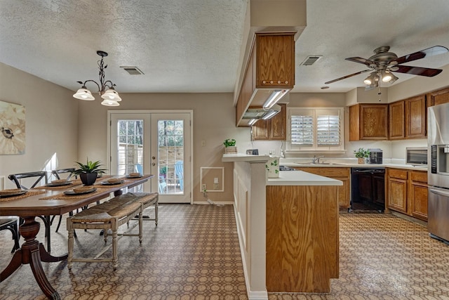 kitchen featuring pendant lighting, french doors, ceiling fan with notable chandelier, a textured ceiling, and stainless steel appliances