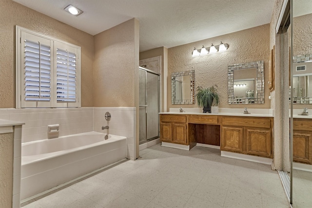 bathroom with vanity, plus walk in shower, and a textured ceiling