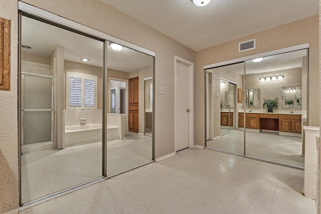 unfurnished bedroom with a textured ceiling and ensuite bath