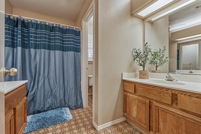 bathroom featuring vanity, toilet, a textured ceiling, and a skylight