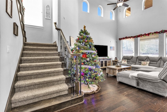 living room featuring ceiling fan, dark hardwood / wood-style flooring, and a towering ceiling