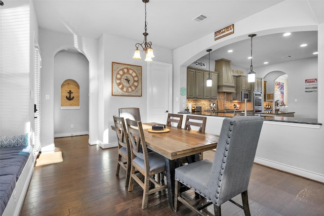 dining room with dark wood-type flooring and a notable chandelier