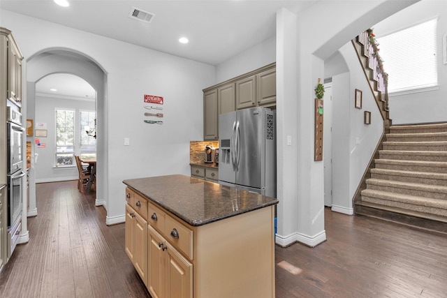 kitchen featuring decorative backsplash, appliances with stainless steel finishes, crown molding, dark wood-type flooring, and a center island