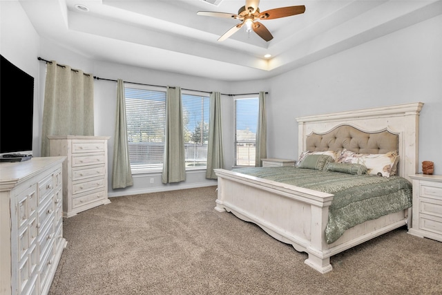 bedroom with ceiling fan, a raised ceiling, and carpet floors