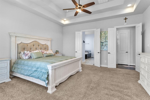 carpeted bedroom featuring a tray ceiling and ceiling fan