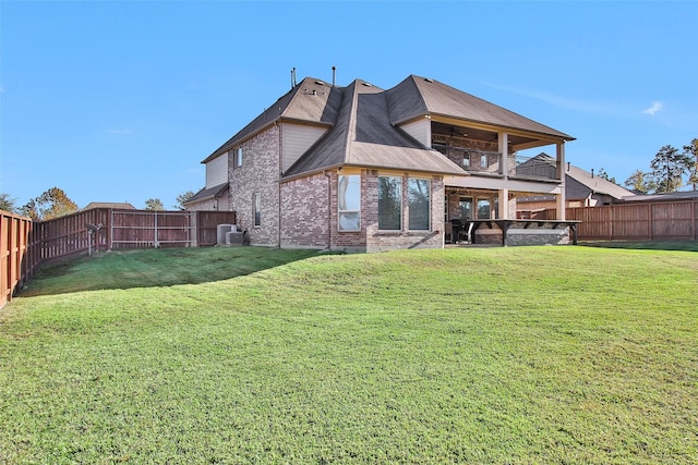 back of property with a lawn, central air condition unit, and a balcony