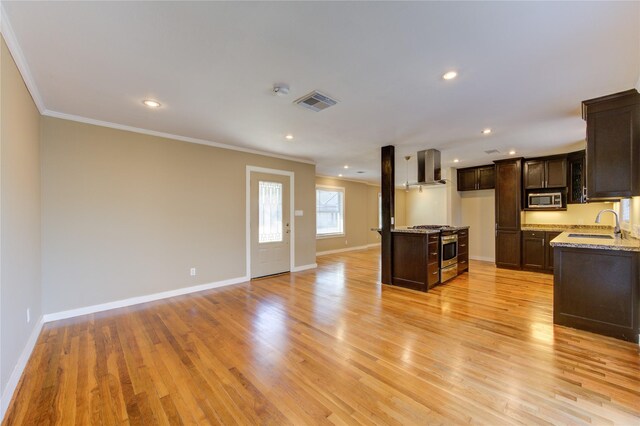 kitchen featuring sink, wall chimney exhaust hood, stainless steel appliances, light stone counters, and light wood-type flooring