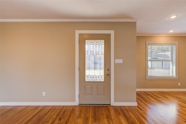 foyer with a wealth of natural light, hardwood / wood-style floors, and ornamental molding