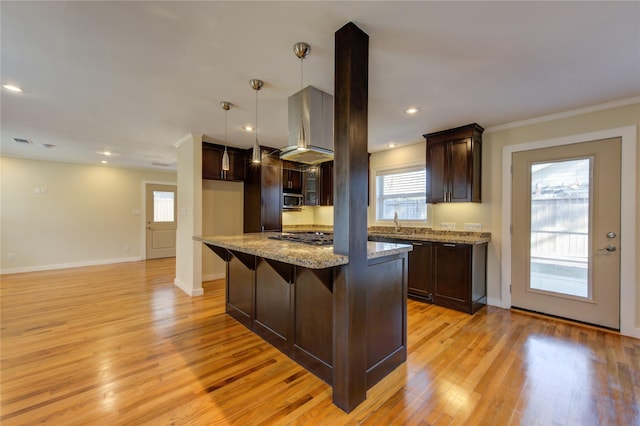 kitchen with pendant lighting, a wealth of natural light, a kitchen island, light stone counters, and stainless steel appliances