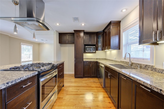 kitchen featuring sink, stainless steel appliances, light stone counters, island range hood, and light wood-type flooring