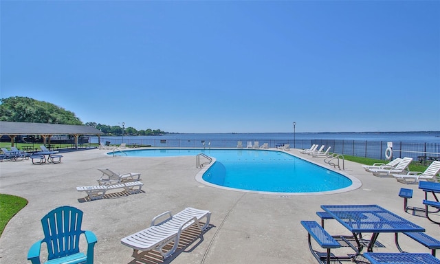 view of pool with a water view and a patio