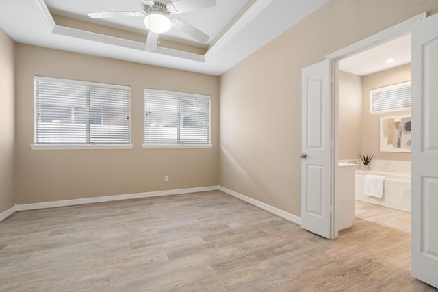 empty room featuring ceiling fan, light hardwood / wood-style floors, and a raised ceiling