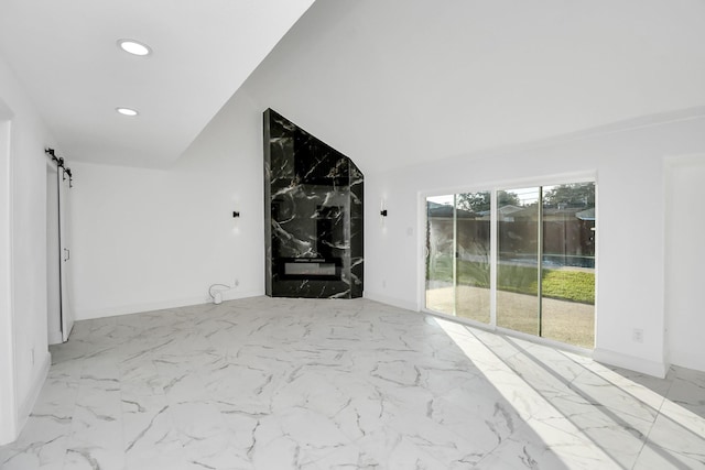 unfurnished room with a barn door and vaulted ceiling