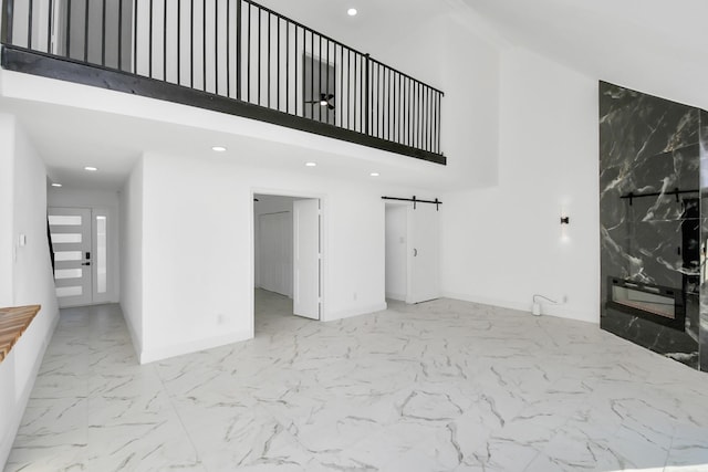 unfurnished living room featuring a high ceiling, a barn door, and a premium fireplace