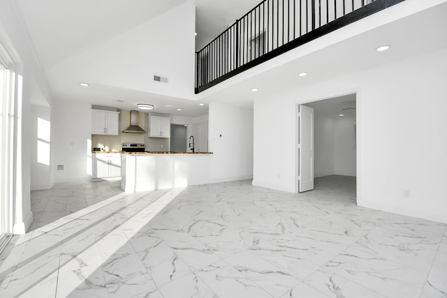 unfurnished living room with a towering ceiling and sink