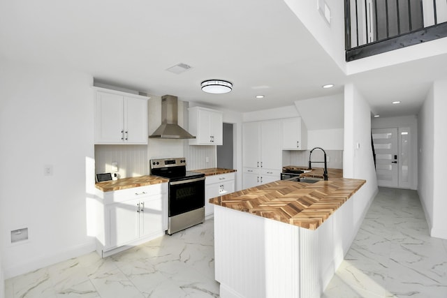 kitchen featuring sink, wall chimney exhaust hood, wood counters, electric stove, and white cabinets