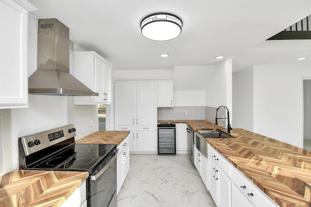 kitchen with wall chimney exhaust hood, white cabinetry, stainless steel appliances, and beverage cooler