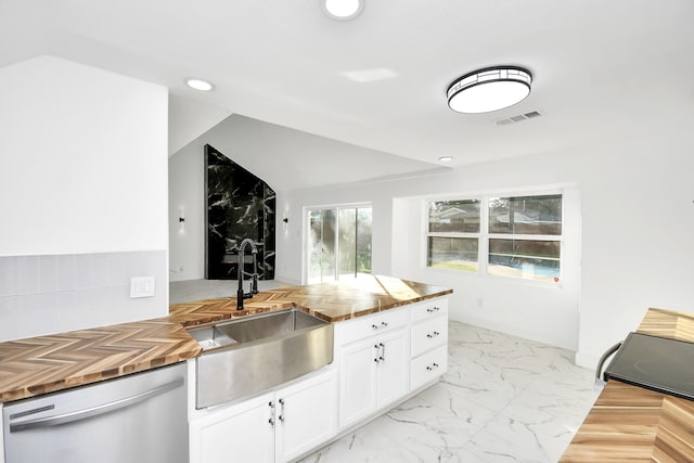 kitchen with stainless steel dishwasher, lofted ceiling, white cabinetry, and sink