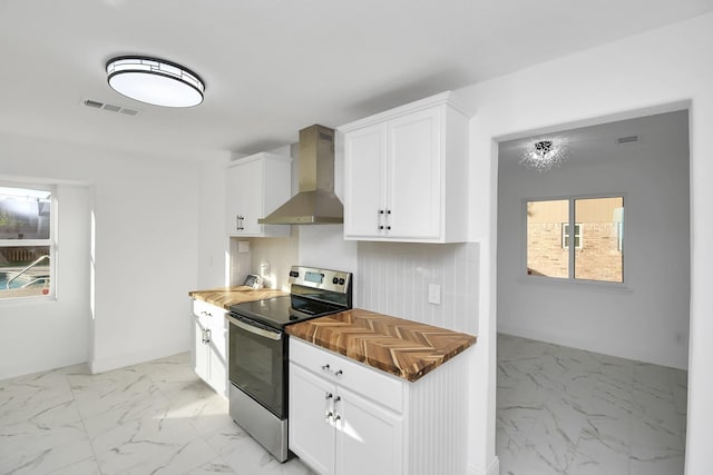 kitchen with electric range, white cabinetry, wall chimney range hood, and tasteful backsplash