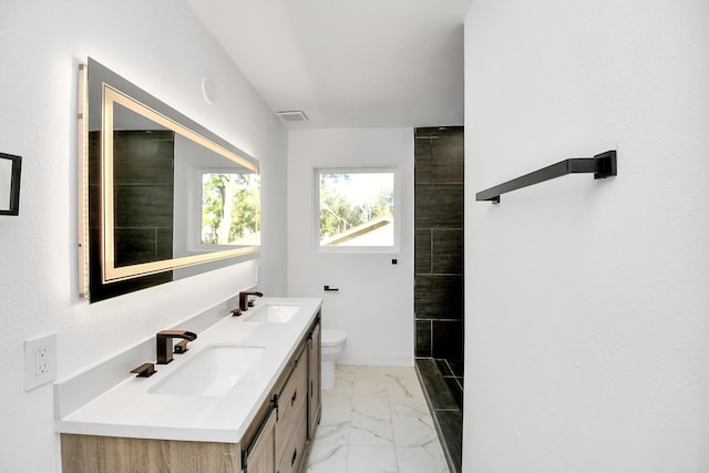 bathroom featuring vanity, toilet, and a tile shower