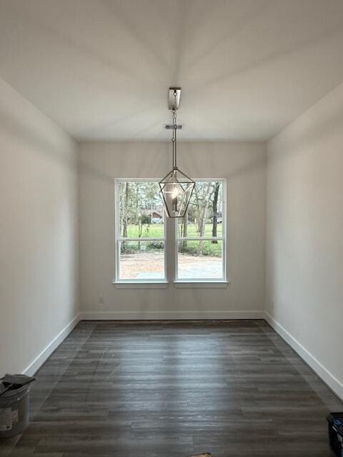 unfurnished dining area with a notable chandelier and dark wood-type flooring