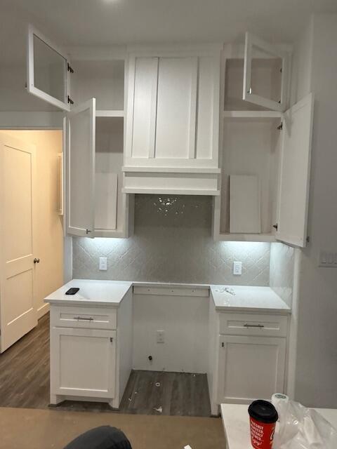 kitchen with white cabinets, backsplash, and range hood