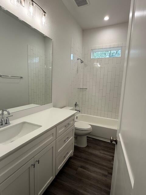 full bathroom featuring hardwood / wood-style flooring, vanity, toilet, and tiled shower / bath