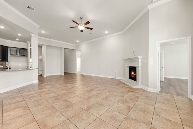 unfurnished living room with ceiling fan, ornamental molding, sink, and light tile patterned floors