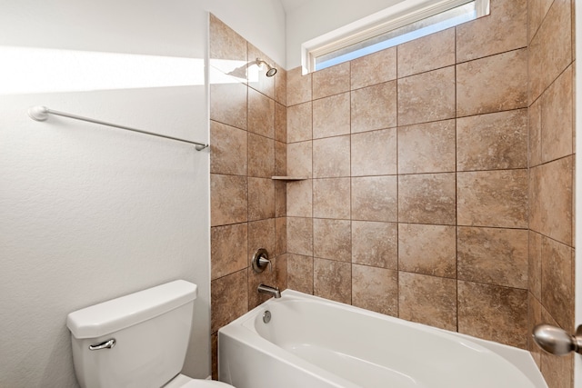 bathroom with tiled shower / bath combo and toilet