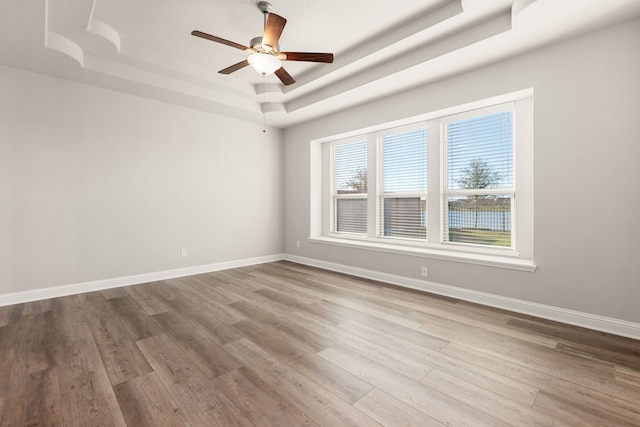 spare room featuring ceiling fan, light hardwood / wood-style floors, and a tray ceiling