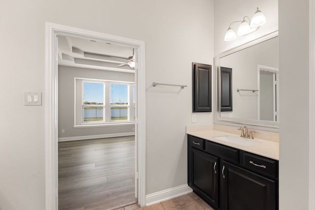 bathroom featuring hardwood / wood-style floors, vanity, a raised ceiling, and ceiling fan