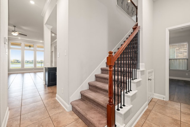 stairway with tile patterned floors, ceiling fan, a healthy amount of sunlight, and crown molding