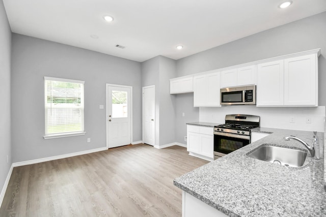 kitchen featuring white cabinets, light stone counters, sink, and appliances with stainless steel finishes