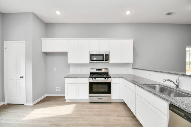 kitchen featuring sink, light stone counters, white cabinetry, and stainless steel appliances